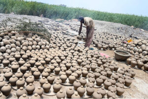 A worker arranging clay-made stuff for draying purpose at his work place at Kumharpara