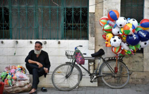 A vendor waiting for customers to sell toys and Plastic balloons hanging on their cycle at roadside footpath in Provincial Capital.