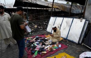 A vendor showcases children's garments at a makeshift stall amidst the debris of last week’s devastating blaze at the H-9 weekly bazaar, which destroyed 2,743 stalls and 625 shops, causing millions in damages in Federal Capital.