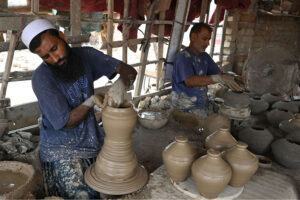 A worker arranging clay-made stuff for draying purpose at his work place at Kumharpara
