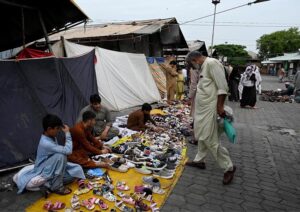 A vendor showcases children's garments at a makeshift stall amidst the debris of last week’s devastating blaze at the H-9 weekly bazaar, which destroyed 2,743 stalls and 625 shops, causing millions in damages in Federal Capital.