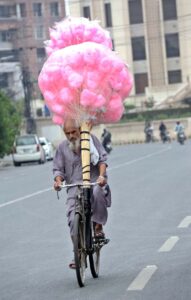 A vendor on a bicycle, loaded with cotton candy, is on his way to sell and earn his livelihood in Provincial Capital.