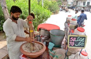A vendor busily prepares traditional summer drink (Sardai) for customers at his roadside setup, offering relief from the heat waves in the city.