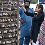 A girl selecting and purchasing keychain with her name from vendor at famous picnic spot Daman-e-Koh