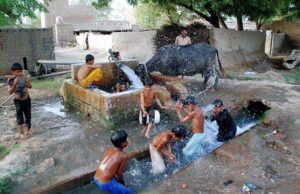 Children splashing and playing in the cool waters of a village tube-well, seeking relief from the intense heat wave.