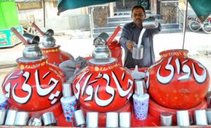 A vendor displaying a traditional drink (lassi) to attract customers during a hot day in the city.