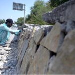 A labourer busy in fixing stones along roadside protection wall at Zero Point in the Federal Capital