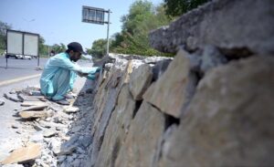 A labourer busy in fixing stones along roadside protection wall at Zero Point in the Federal Capital