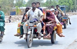 A gypsy family travelling on a tricycle rickshaw heading toward their destination.