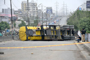 An oil tanker overturned at the Baloch Colony flyover, rescue workers and other officials are seen standing at the spot on Thursday.