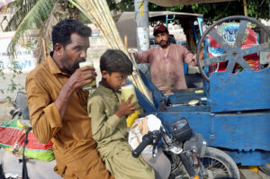 Father and son beat the heat with traditional sugarcane juice while sitting on their bike in Provincial Capital