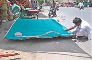 A worker is busy preparing traditional curtain (chick) at his roadside setup.