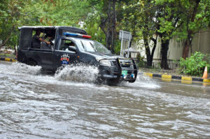 Security forces' vehicles navigate a flooded road amid heavy rain in the provincial capital.