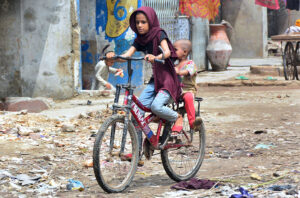 A girl enjoying riding the bicycle in the street at Latifabad.