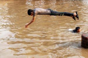 A young boy dives into the canal for getting relief from the scorching heat in the provincial capital city-