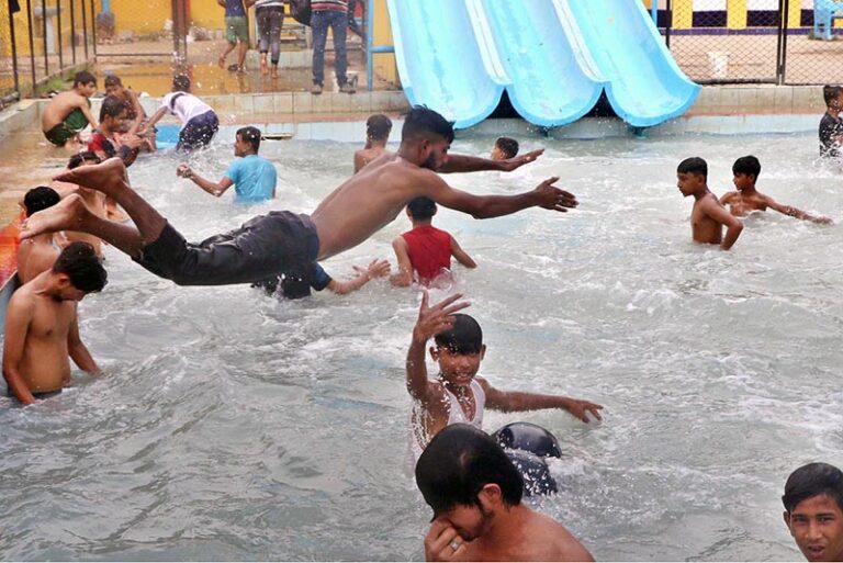 A young boy dives into a swimming pool at a water park, where