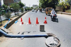 A main road in Bahawalpur city with an uncovered sewerage system, risking the safety of numerous vehicles.