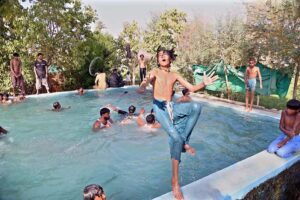 A young boy dives into a swimming pool at a water park, where youngsters splash, jump, and swim and seeking relief from the heat waves in the Provincial Capital city.
