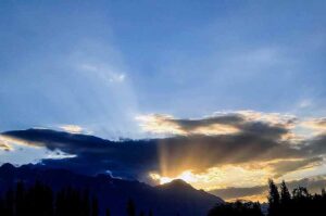 -A mesmerizing view: Sunset rays pierce through dark clouds, casting a stunning, colorful skyline over the city.