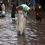 People passing through accumulated water on the road during rain in the Provincial Capital
