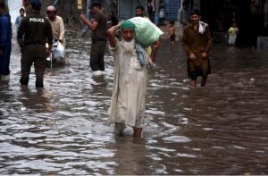 People passing through accumulated water on the road during rain in the Provincial Capital