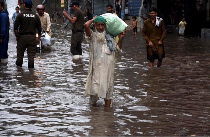 People passing through accumulated water on the road during rain in the Provincial Capital