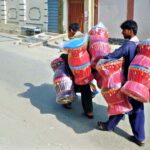 A street vendor carries traditional bamboo sitting stools on their shoulders, to sell them in the city streets