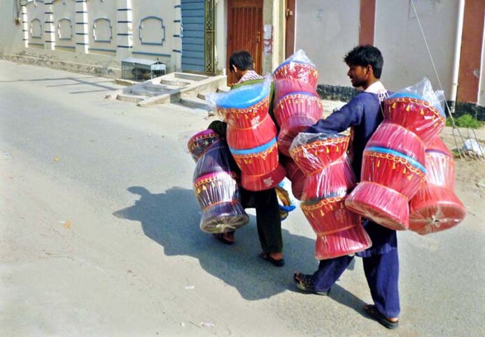 A street vendor carries traditional bamboo sitting stools on their shoulders, to sell them in the city streets