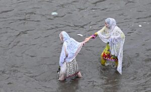 Women passing through accumulated water on the road during rain in the Provincial Capital