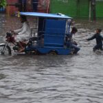 Women passing through accumulated water on the road during rain in the Provincial Capital