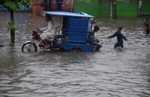 Women passing through accumulated water on the road during rain in the Provincial Capital