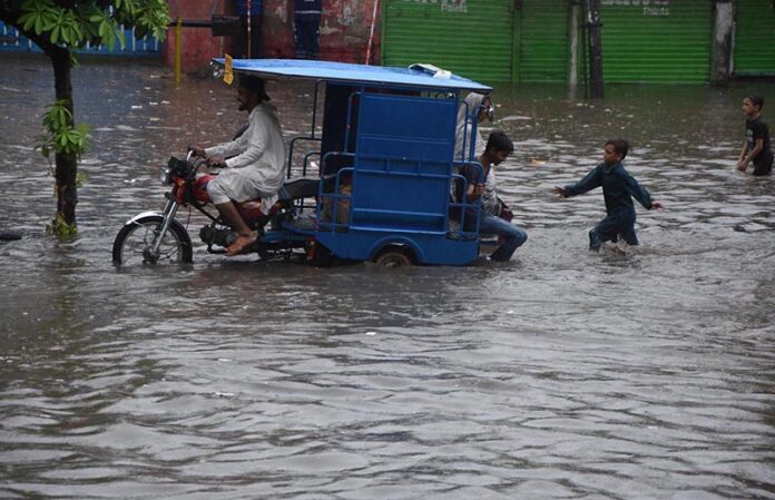 Women passing through accumulated water on the road during rain in the Provincial Capital