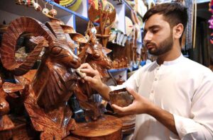 A craft boy giving polish to a decoration piece of National animal Markhor at his shop.