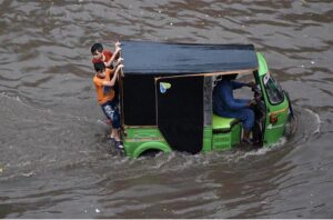 Women passing through accumulated water on the road during rain in the Provincial Capital