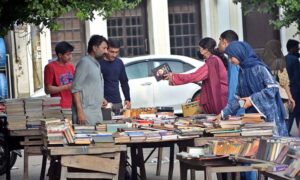Women selecting and purchasing old books from a roadside stall at Mall Road in the Provincial Capital