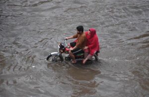 Women passing through accumulated water on the road during rain in the Provincial Capital