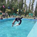 Youngsters jumping and taking bath in swimming pool to get relief from hot weather in the city