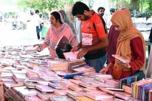 Women selecting and purchasing old books from a roadside stall at Mall Road in the Provincial Capital