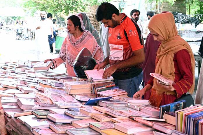 Women selecting and purchasing old books from a roadside stall at Mall Road in the Provincial Capital