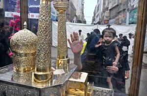 Volunteer showering water on mourners attending Youm-e-Ashura procession on 10th of Holy Month of Muharramul Harram at Station Road to keep them cool during hot and humid weather in the city.