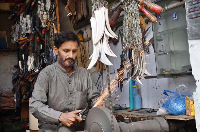 Blacksmith busy in sharpening knives to be used during the procession of Muharram at Chowk Khuda Bakhsh Road Nonaria