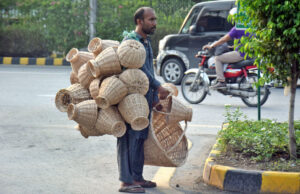 worker attracts customers by looking at handmade palm leaf home decorations and used baskets on the roadside.