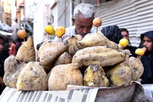 A vendor selling roasted sweet potatoes, served hot and aromatic, enticing customers with tradition at old fish market road.