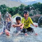 Children enjoy bathing in a stream and get relief from the hot weather in the city
