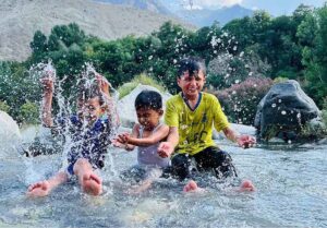 Children enjoy bathing in a stream and get relief from the hot weather in the city