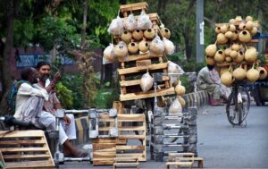 Street vendors waiting the customers while displaying hand-made domestic use items (wooden stools and birds Nests) to the customers on their Cycles at roadside.