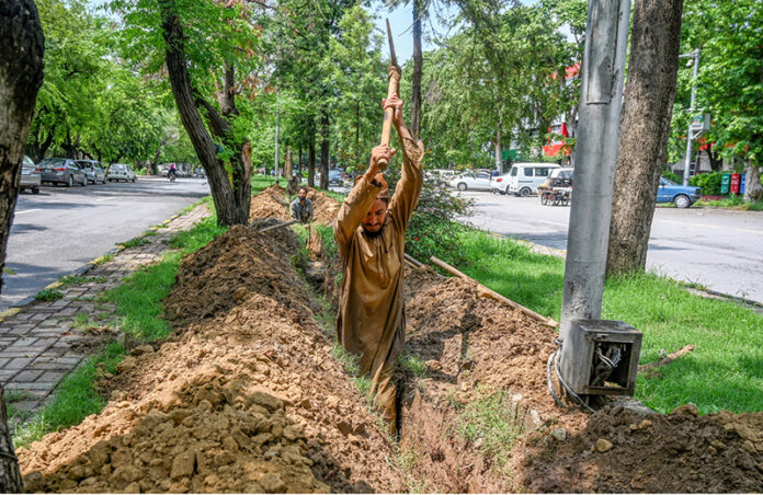 A laborer busy digging the ground to lay cable for a CCTV camera at Sector F-7/2