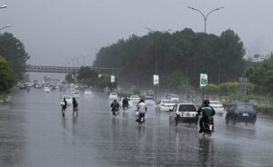 Vehicles and bikers make their way through heavy rain at Zero Point in the Federal Capital