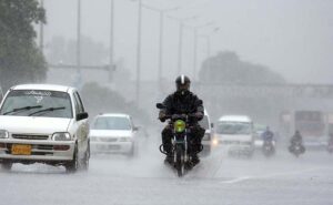 A motorcyclist rides through heavy rain on the Islamabad Expressway, facing reduced visibility and slippery road conditions due to torrential rain .