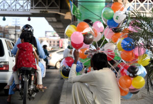 A street vendor displaying balloons to attract customers while sitting on the roadside at Liaquat Bagh